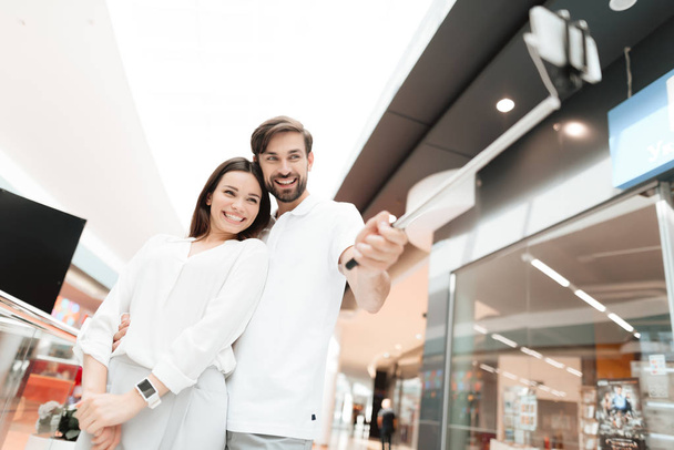 Man and woman in shopping mall. Couple is taking selfie with selfie stick. - Fotografie, Obrázek