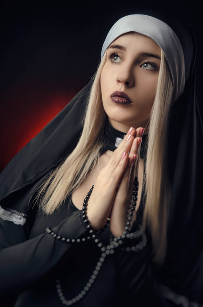 Fine art portrait of a novice nun in deep prayer with rosary - Photo, Image