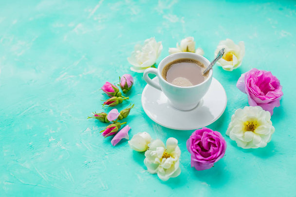 barevné květy a ranní šálek kávy na modrém pozadí. koncept horkého nápoje, káva k snídani. minimální plochou lay. Romantický stůl s horkým nápojem cup a roses.beautiful květiny pro - Fotografie, Obrázek