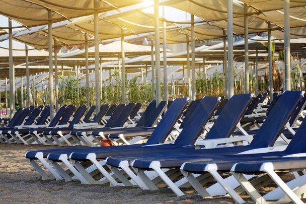 Ligstoelen met parasol op het strand. Toeristenindustrie. - Foto, afbeelding