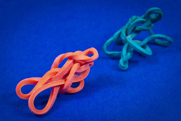 Old blue cracked and new red twisted rubber bands centered on blue background with copy space - 写真・画像