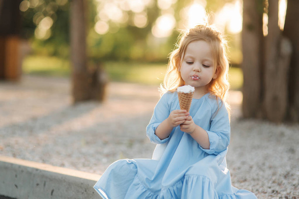 Krásná malá dívka v modrých šatech jíst zmrzlinu - Fotografie, Obrázek