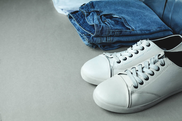 Jeans blu e sneakers bianche su sfondo grigio
. - Foto, immagini