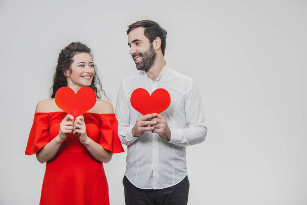 Beautiful attractive, cheerful, positive pair. Are married Hold large red cards in their sleeves. When they look at each other. - Fotoğraf, Görsel