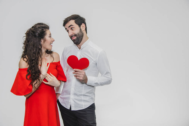 Family, holidays, Valentines Day. Love people concept - a big plan. Hold the red paper heart. White background. Dressed in a white shirt and a red dress. - Фото, изображение