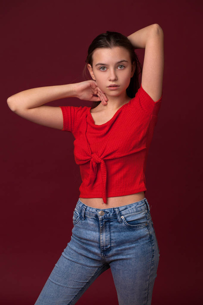 Portrait of a young teen girl close-up without makeup, isolated on red background - Foto, immagini