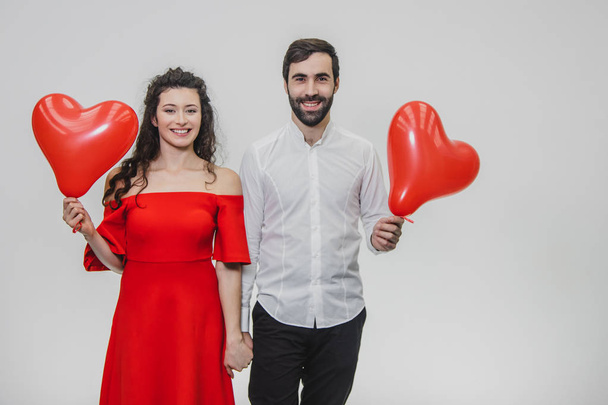 Beautiful romantic couple isolated on white background. An attractive young woman and beautiful hands raise balloons in the shape of the heart. Smiling. - Photo, Image