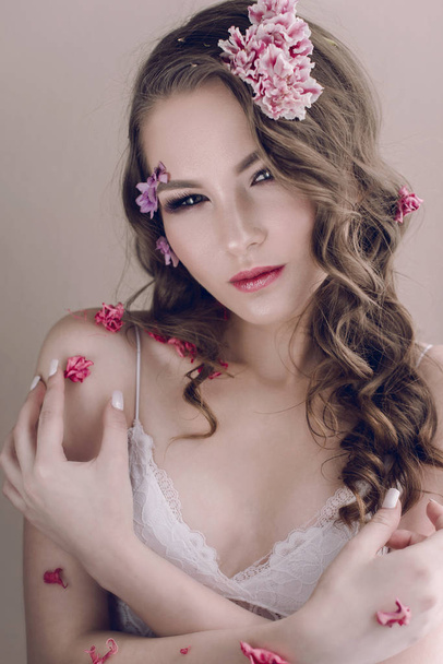Cosméticos e manicure. Retrato de close-up de mulher atraente com flores secas no rosto, cor pastel, maquiagem perfeita e pele. Retrato retocado de primavera fresco, na moda
 - Foto, Imagem