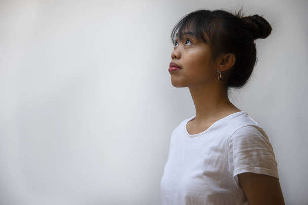 αρκετά σκούρο δέρμα έφηβος νέοι Φιλιππίνων γυναίκα με μακριά μαλλιά σε λευκό T-shirt με ασημένιο σκουλαρίκι φόντο - Φωτογραφία, εικόνα
