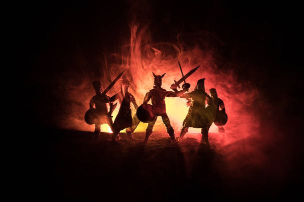 Средневековая сцена боя. Силуэты фигур как отдельные объекты, борьба между воинами на темном, тонированном туманном фоне. Ночная сцена. Селективный фокус
 - Фото, изображение