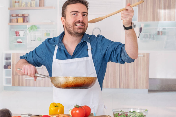 Ο άνθρωπος στην κουζίνα στο σπίτι δοκιμάζει το φαγητό - Φωτογραφία, εικόνα