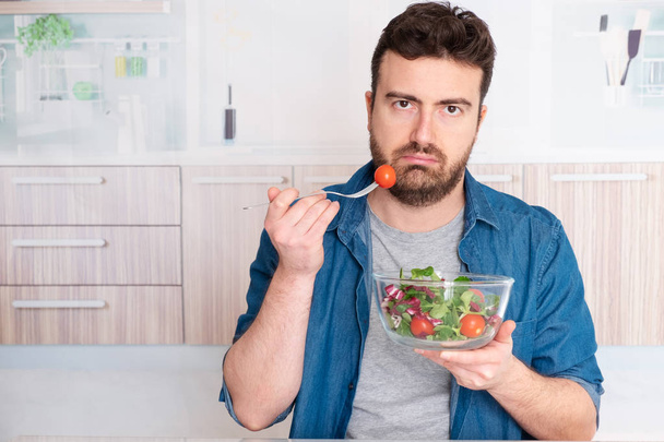 Сумний чоловік змушений їсти салат для схуднення
 - Фото, зображення