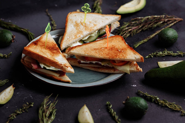 Close up of delicious homemade sandwiches on a black background with vegetables and fruits - Zdjęcie, obraz