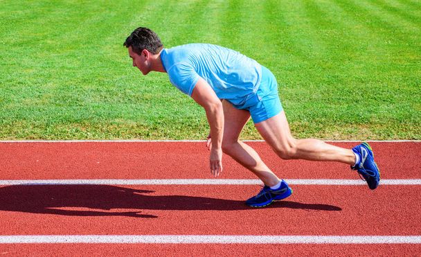 Hogyan viselkedni elkezd futás. Boost speed koncepció. Férfi sportoló runner nyomja le a kezdő pozíció stadion út süt a nap. Runner rögzített mozgás, csak a verseny kezdete után. Futó sprint versenyen-stadionban - Fotó, kép