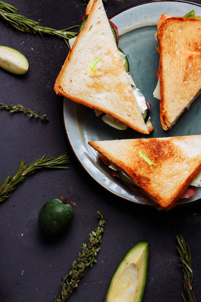 Delicious Breakfast, food, morning concept. Closeup top view of fresh homemade sandwiches on black background with feijoa and avocado. - Fotó, kép