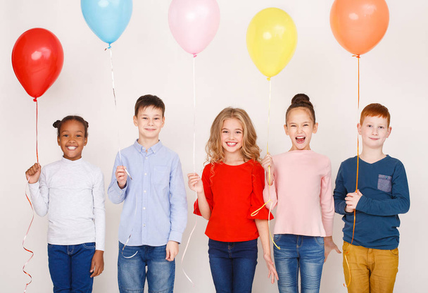 Група дітей з різнокольоровими повітряними кулями над стіною
 - Фото, зображення