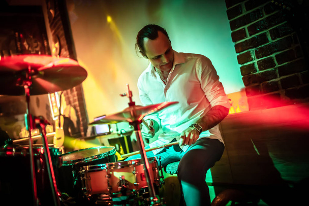 Drummer playing on drum set on stage. Warning - Focus on the drum, authentic shooting with high iso in challenging lighting conditions. A little bit grain and blurred motion effects. - Photo, Image
