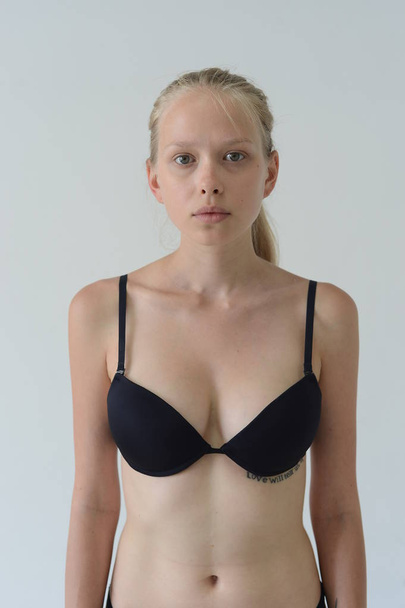 model tests girl in black lingerie with tattoo posing in Studio on grey background - Фото, зображення