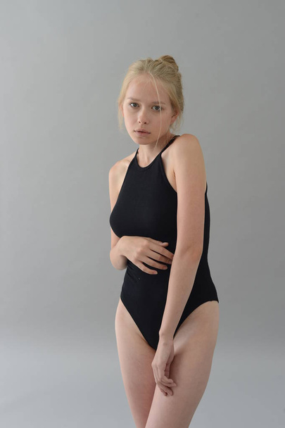 girl in black swimsuit with white hair posing in Studio on grey background - 写真・画像