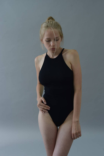 girl in black swimsuit with white hair posing in Studio on grey background - Zdjęcie, obraz