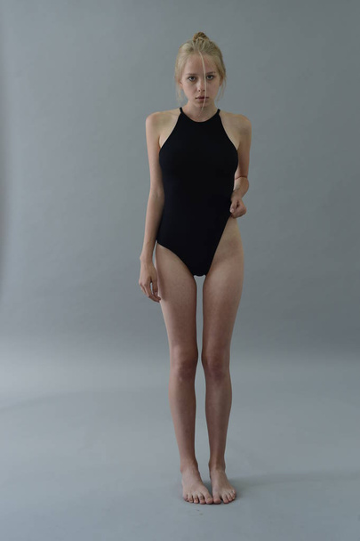 girl in black swimsuit with white hair posing in Studio on grey background - Фото, изображение