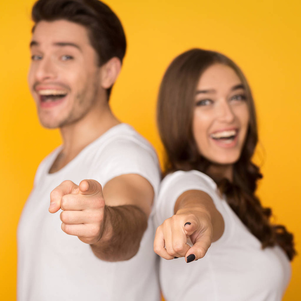 Joyful couple pointing fingers at camera over background - Photo, Image