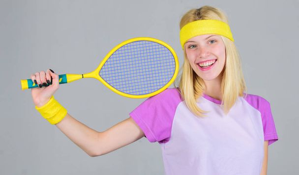Girl adorable blonde play tennis. Sport for maintaining health. Active leisure and hobby. Athlete hold tennis racket in hand on grey background. Tennis sport and entertainment. Tennis club concept - Foto, immagini