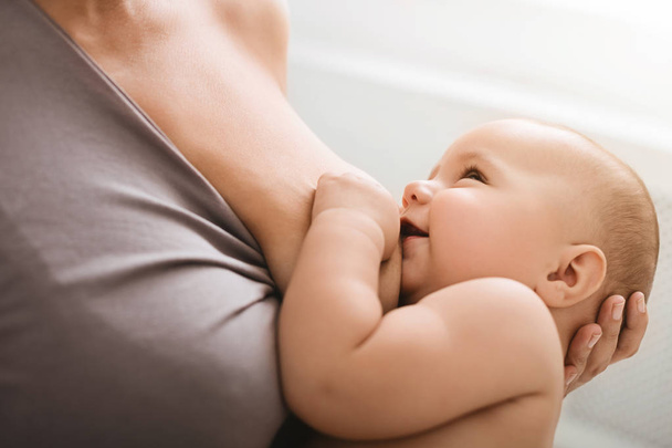 Lachende baby op zoek in moeders ogen, tijdens borstvoeding - Foto, afbeelding