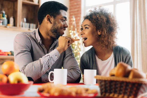 Joven pareja negra alimentándose mutuamente en la cocina
 - Foto, Imagen