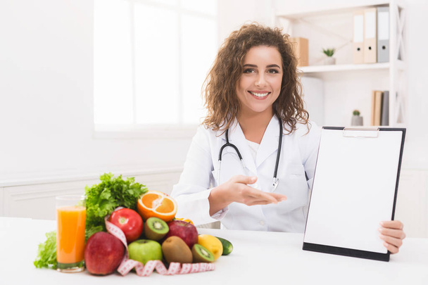 Woman nutritionist pointing on blank clipboard at office - Foto, immagini