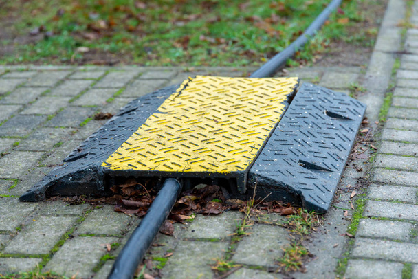 Czarny i żółty kabel most prowadzi przez gruby kabel do ochrony. - Zdjęcie, obraz