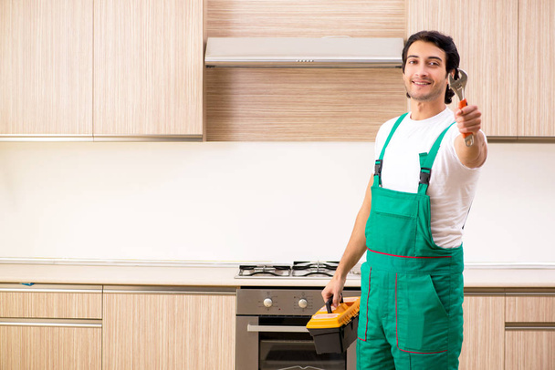 jovem empreiteiro reparação forno na cozinha  - Foto, Imagem