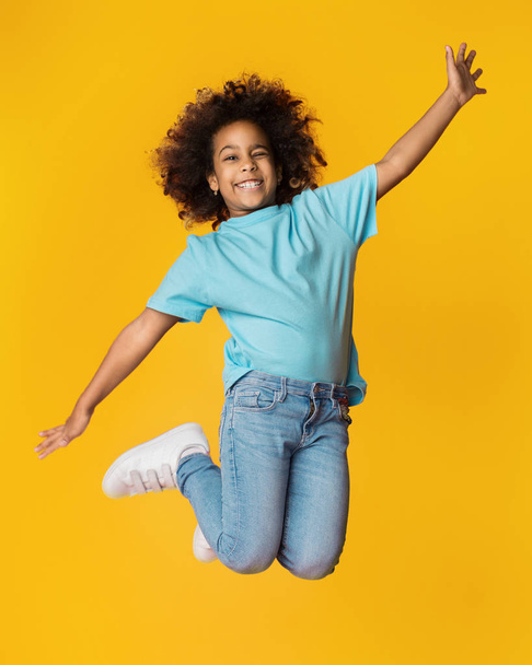 kleines afrikanisch-amerikanisches Mädchen springt über Studiohintergrund - Foto, Bild