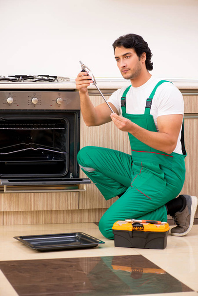 jonge aannemer reparatie oven in keuken  - Foto, afbeelding