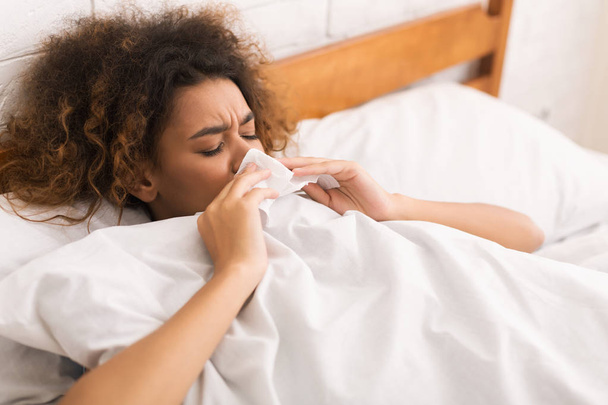 Jeune femme malade qui se mouche au lit
 - Photo, image
