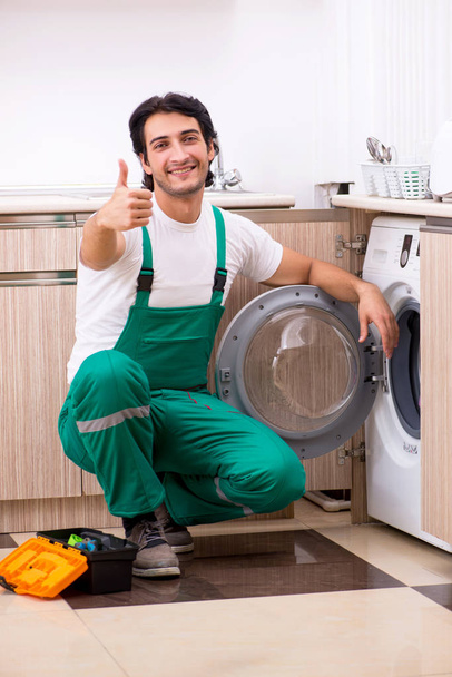 Young contractor repairing washing machine in kitchen - Photo, image