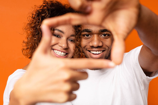 Чорний чоловік і жінка показують знак рамки руками
 - Фото, зображення