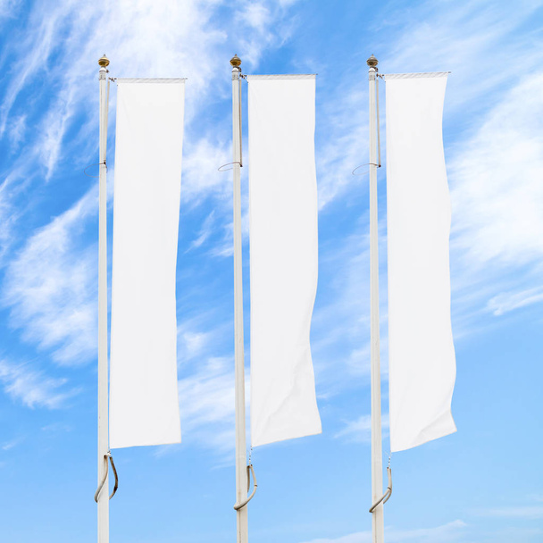 Три порожні білі прапори на флагштоках проти хмарного блакитного неба, макет корпоративного прапора для рекламного логотипу, тексту або символу, шаблон фірмового прапора з копіювальним простором
 - Фото, зображення