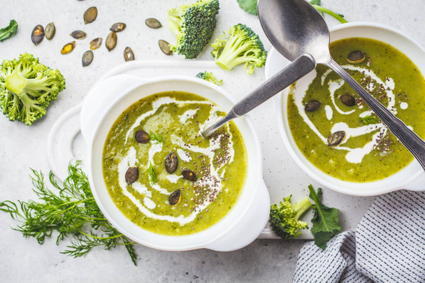 Vegan detox broccoli cream soup with coconut cream and pumpkin seeds in a white bowl. Plant based food concept. - Fotoğraf, Görsel