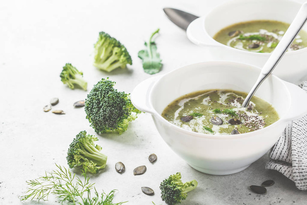 Vegan detoks kremalı brokoli çorbası ile Hindistan cevizi kreması ve kabak tohumu beyaz bir kase. Bitki esaslı gıda kavramı. - Fotoğraf, Görsel