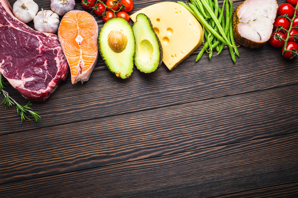 ketogene Low-Carbs-Zutaten für eine gesunde Gewichtsabnahme Ernährung, Draufsicht, Kopierraum. Keto-Lebensmittel auf hölzernem Hintergrund: Fleisch, Fisch, Avocado, Käse, Gemüse, Nüsse. Saubere Ernährung, gesunde Fette  - Foto, Bild