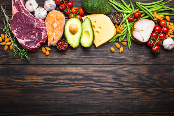 Ketogenic low carbs ingredients for healthy weight loss diet, top view, copy space. Keto foods on wooden background: meat, fish, avocado, cheese, vegetables, nuts. Clean eating, healthy fats  - Φωτογραφία, εικόνα