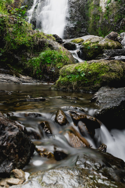 Gebirgswasserfall im Sommerwald. Fluss mit nassen Steinen und Pflanzen am Ufer. - Foto, Bild