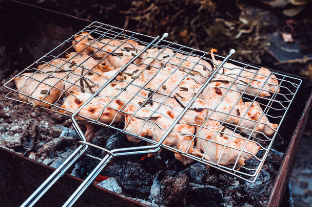 Cooking meat on fire. Fry meat on metal grid. Barbecue on nature for party. - Foto, imagen