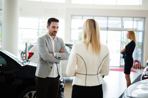 Grupo de felices consultores de ventas de coches hermosos que trabajan dentro de la sala de exposición de vehículos
 - Foto, Imagen