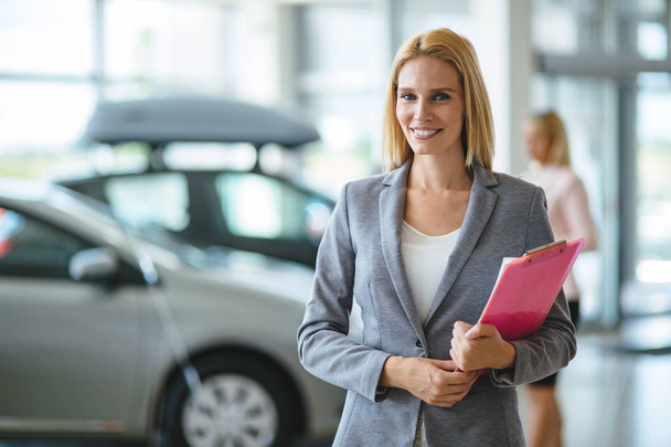 Picture of professional female salesperson working in car dealership - Zdjęcie, obraz