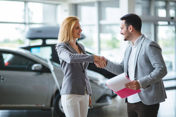 Professional woman salesperson during work with customer at car dealership. - Zdjęcie, obraz