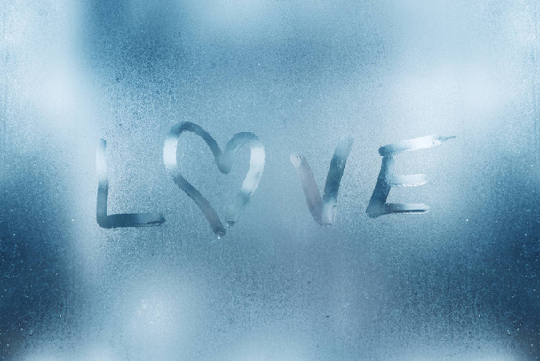 The heart is painted on the misted glass in the winter. - Foto, Imagen