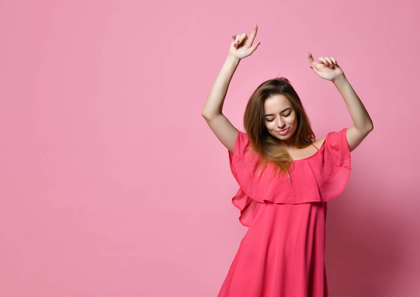 Portrait of brunette Caucasian girl dancing against pink wall with smile, rejoicing good mood. - Photo, image