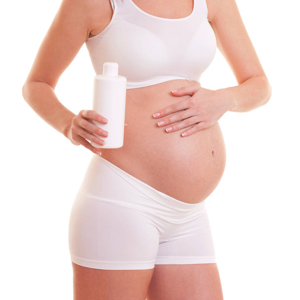 Velmi těhotná žena použití anti strie krém na jejím těle. Izolované na bílém. Péče o kůži v období těhotenství. - Fotografie, Obrázek